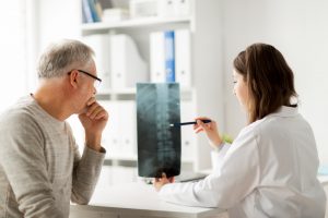 lekarz omawiający zdjęcie rentgenowskie kręgosłupa z pacjentem