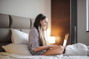 kobieta używająca laptopa na łóżku